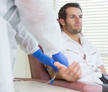 Young male patient receiving intravenous treatment in chemo room